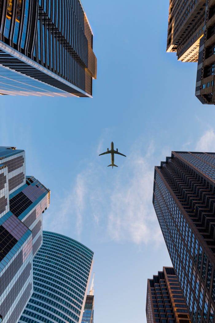 our-services-01 Airplane flies over Chicago's modern skyscrapers against a clear sky, highlighting urban architecture.